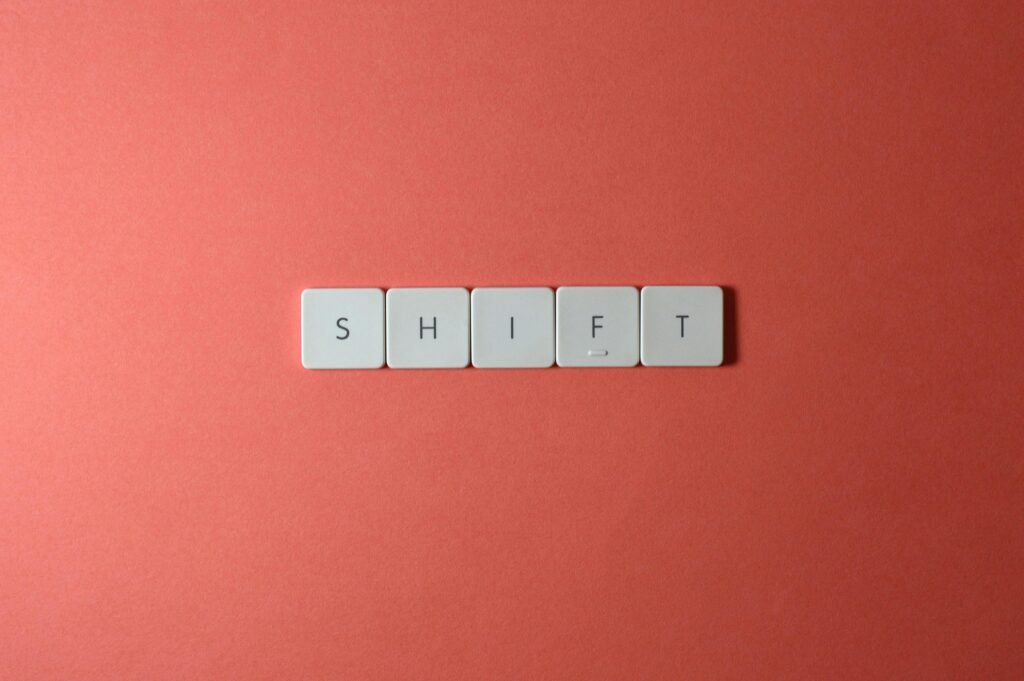 Close-up of keyboard keys spelling 'shift' on a plain red surface.